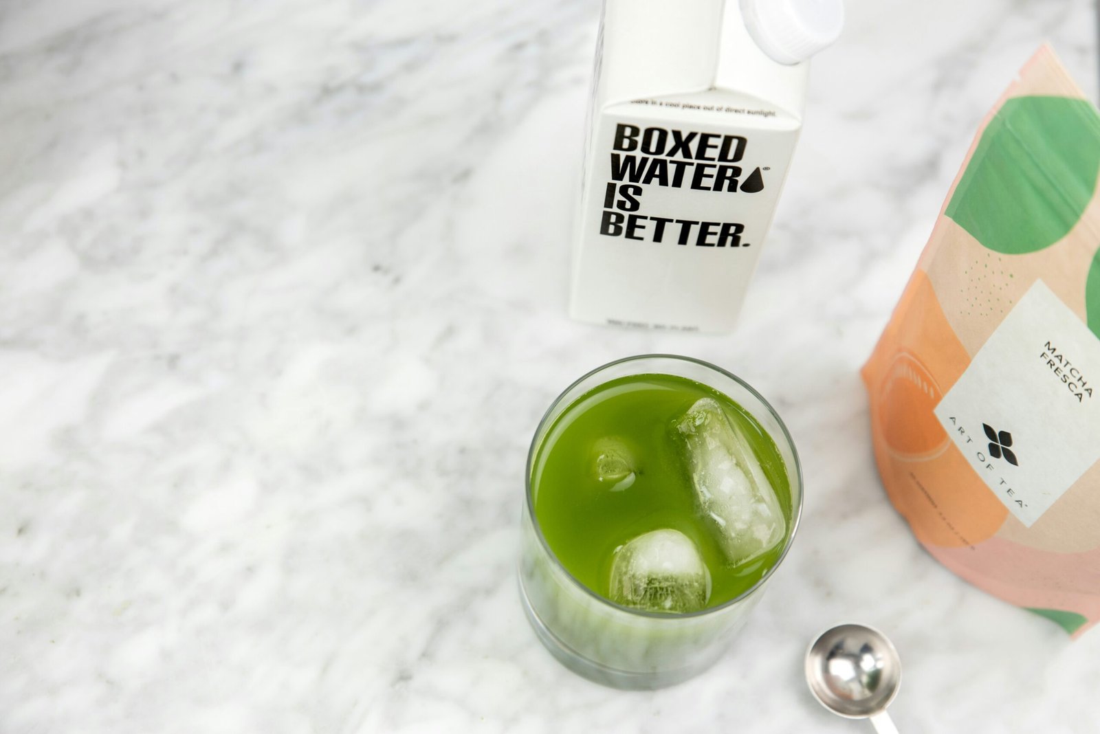 a glass of green liquid next to a bottle of water